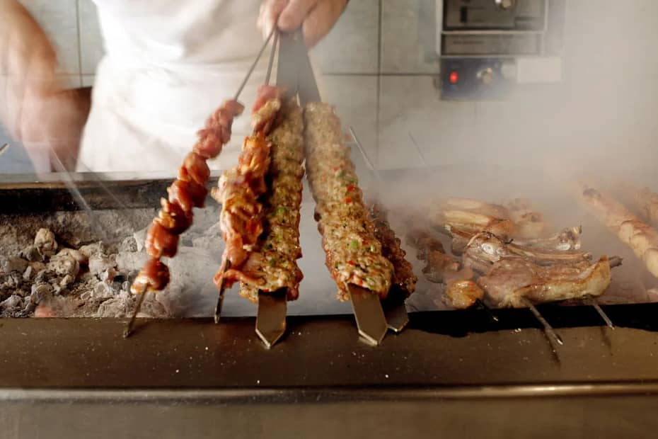 A set of skewers filled with various meats on a charcoal grill.