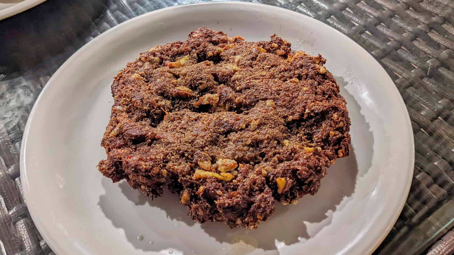 Chapli kabab are thin ground beef patties made with aromatics and spices. Unlike your usual grilled kebabs, Chapli Kabab are fried so they’re browned and crisp on the outside whilst staying tender on the inside. Presented in this shot on a white plate.